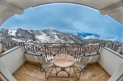 a table and chairs on a balcony with a view at Milmari Resort M16 Markovic in Kopaonik