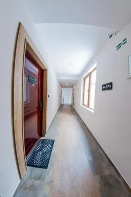 an empty hallway with a red door and a wooden floor at Milmari Resort M16 Markovic in Kopaonik
