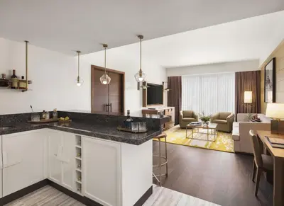 a kitchen with white cabinets and a living room at Viceroy Kopaonik Resort & Spa in Kopaonik