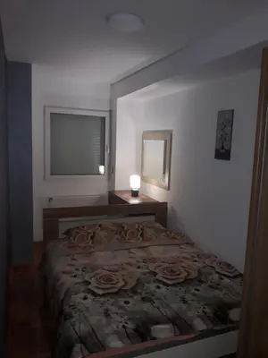 a bedroom with a bed with a lamp and a window at Apartman Vranje in Vranje