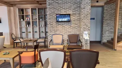 a room with chairs and tables and a tv on a brick wall at Apartman No1,Župa Wellness & Spa Kopaonik in Kopaonik