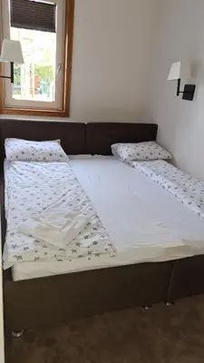 a bed with two white sheets and a window at Apartman No1,Župa Wellness & Spa Kopaonik in Kopaonik