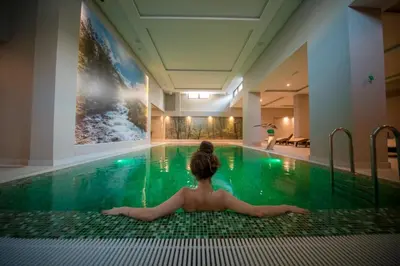 a woman laying in a swimming pool at SREBRNA PLANINA Spa & Resort in Kopaonik