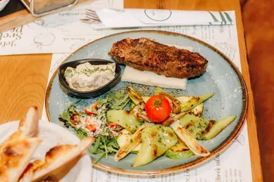 a plate of food with meat and vegetables on a table at SREBRNA PLANINA Spa & Resort in Kopaonik