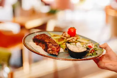 a person holding a plate with food on it at SREBRNA PLANINA Spa & Resort in Kopaonik