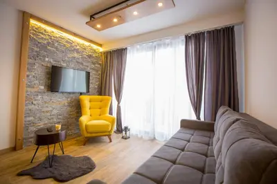a living room with a couch and a yellow chair at SREBRNA PLANINA Spa & Resort in Kopaonik