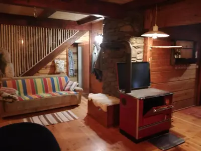 a living room with a tv and a couch and a stone wall at Brvnara Aleksic in Kraljevo