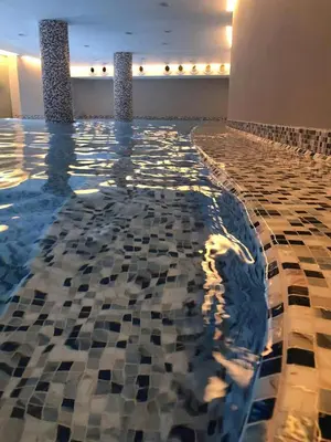 a swimming pool with a tiled floor and two columns at Apartman Paradiso 211 in Vrnjačka Banja