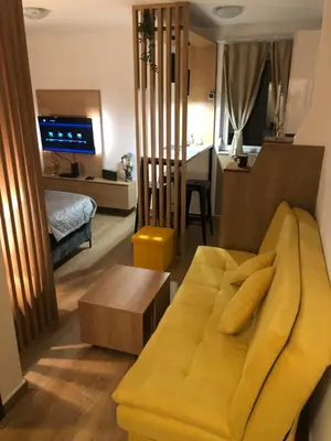 a living room with a yellow couch and a bedroom at TeonaLux Kraljevi Cardaci 5a/22 in Kopaonik