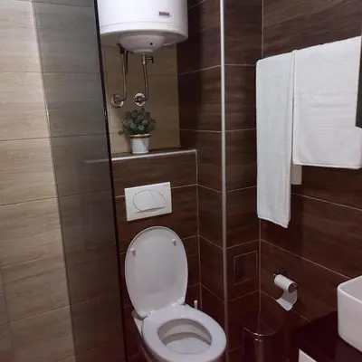 a bathroom with a toilet and a sink and towels at Apartman Alba in Kopaonik
