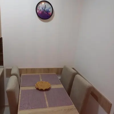 a dining room table with a clock on the wall at Apartman Alba in Kopaonik