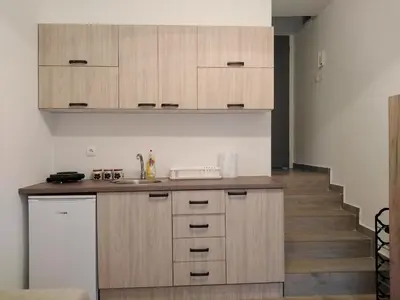 a kitchen with wooden cabinets and a staircase at Apartman TiA Vrnjacka Banja in Vrnjačka Banja