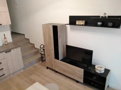 a living room with a tv and a staircase at Apartman TiA Vrnjacka Banja in Vrnjačka Banja