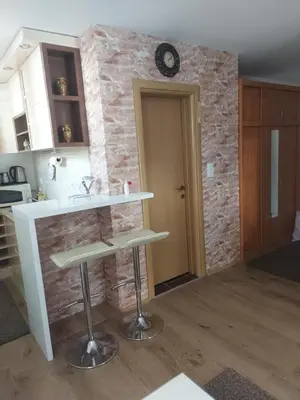 a kitchen with a counter and a clock on a brick wall at Kopaonik,Sunčana dolina,Apart-Pavlovic in Kopaonik