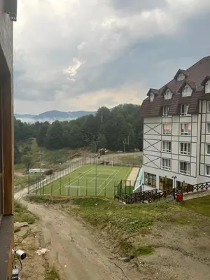a tennis court in front of a building with a tennis court at Apartman Kostic Kraljev Konak in Kopaonik
