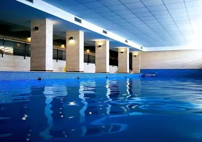 a swimming pool with blue water in a building at Dream Milmari L12 Apartman in Kopaonik