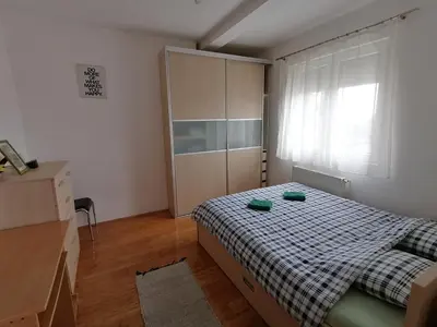 a bedroom with a bed and a dresser and a window at Apartman Breza in Kruševac