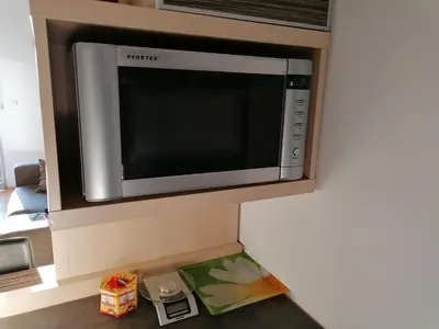 a microwave oven above a kitchen counter with food at Apartman Breza in Kruševac