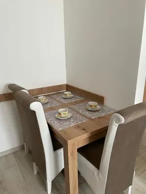 a dining room table with chairs and a wooden table with plates at Kraljevi Konaci -Apartmani Bajka in Kopaonik
