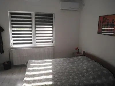 a bedroom with a bed and a window with blinds at APARTMAN “POD KRALJEVICOM” in Zaječar