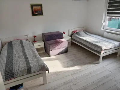 a bedroom with two beds and a chair at APARTMAN “POD KRALJEVICOM” in Zaječar
