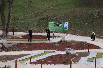 a group of people walking around a park with a slide at Idila in Kruševac