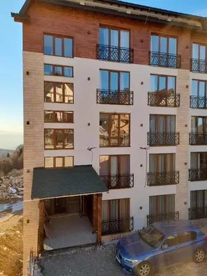 an apartment building with a car parked in front of it at Prezident Marta in Kopaonik