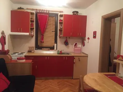 a kitchen with red cabinets and a sink and a table at Vila Boris, Apartman Aleksej - Kopaonik in Kopaonik