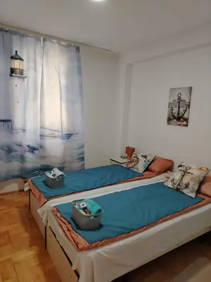 two beds in a room with a painting on the wall at Apartman Domina in Kruševac