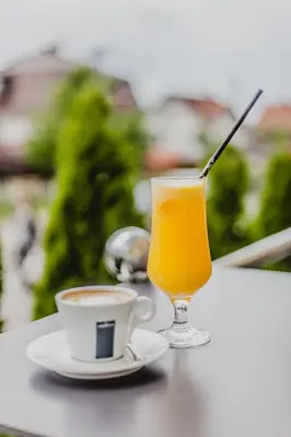 a glass of orange juice and a cup of coffee on a table at Apartman Viva in Vrnjačka Banja