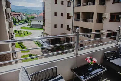a balcony with a table and chairs and a view of a street at Apartman Viva in Vrnjačka Banja