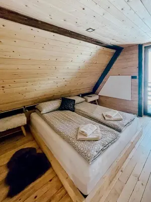 a bed in a room with a wooden wall at K2 Chalet in Kopaonik