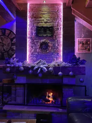 a living room with a stone fireplace with purple lights at K2 Chalet in Kopaonik