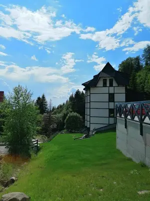 a white building with a black roof on a grass field at Vila Irina Kopaonik - Apartman Jovana in Kopaonik
