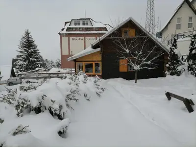 a snow covered yard with a building and a tower at kuća za odmor marković in Kopaonik