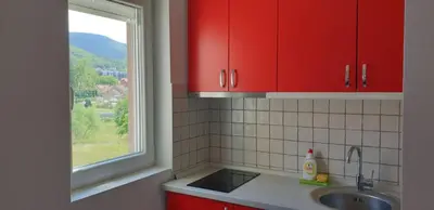 a kitchen with red cabinets and a sink and a window at Lux Apartman Ristić 2 in Soko Banja