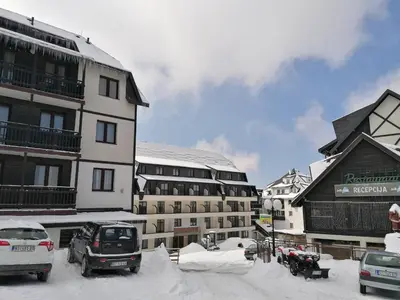 a snow covered parking lot in front of a building at Apartman Div Kopaonik in Kopaonik
