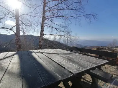 a wooden picnic table with a view of the mountains at Apartman Div Kopaonik in Kopaonik