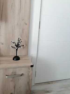 a vase with white flowers on a wooden table next to a door at Apartman Div Kopaonik in Kopaonik