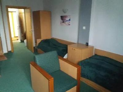 a hotel room with two beds and a chair at Kopaonik Vila Nikola 306 centar in Kopaonik