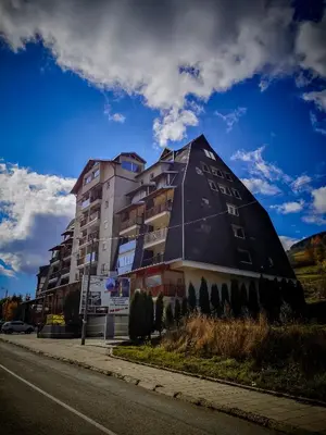 a building with a pyramid shaped roof on a street at STAR apartman Brzece Kopaonik in Brzeće