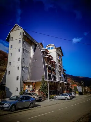 a large building with cars parked in front of it at STAR apartman Brzece Kopaonik in Brzeće