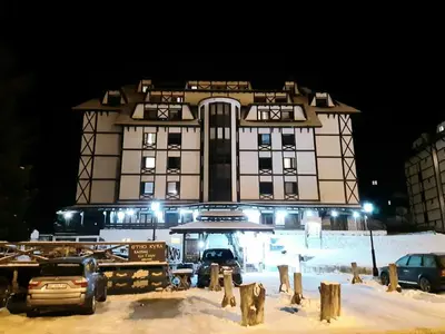 a large building with cars parked in front of it at Apartman Vrhovi Kopaonik Vila Nikola Centar in Kopaonik