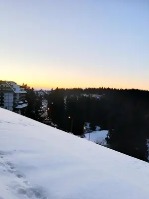 a snow covered slope with the sunset in the background at Apartman Vrhovi Kopaonik Vila Nikola Centar in Kopaonik