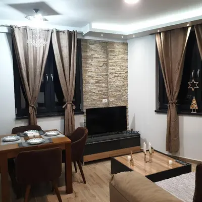 a living room with a table and a television at Apartman Noalux Kopaonik in Kopaonik