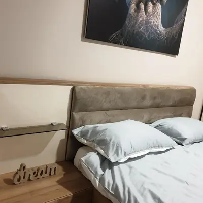 a bed with two pillows and a picture on the wall at Apartman Noalux Kopaonik in Kopaonik
