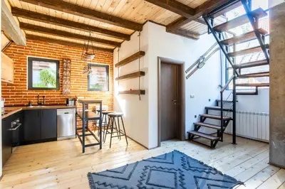 a kitchen with a brick wall and a spiral staircase at Kežman Mountain Houses in Kopaonik