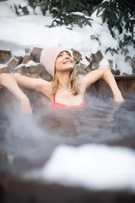 a woman sitting in a bath tub with snow at Kežman Mountain Houses in Kopaonik