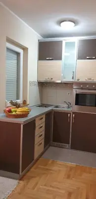 a kitchen with brown cabinets and a bowl of fruit on a counter at Apartman Nikola- 4 ZVEZDICE minimalno 3 nocenja za rezervaciju in Vrnjačka Banja
