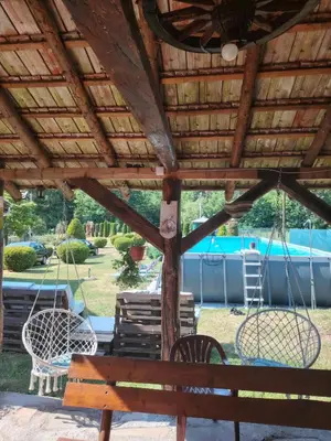 a wooden pergola with chairs and swings in a yard at Apartmani Mihajlovic Sisevac in Sisevac